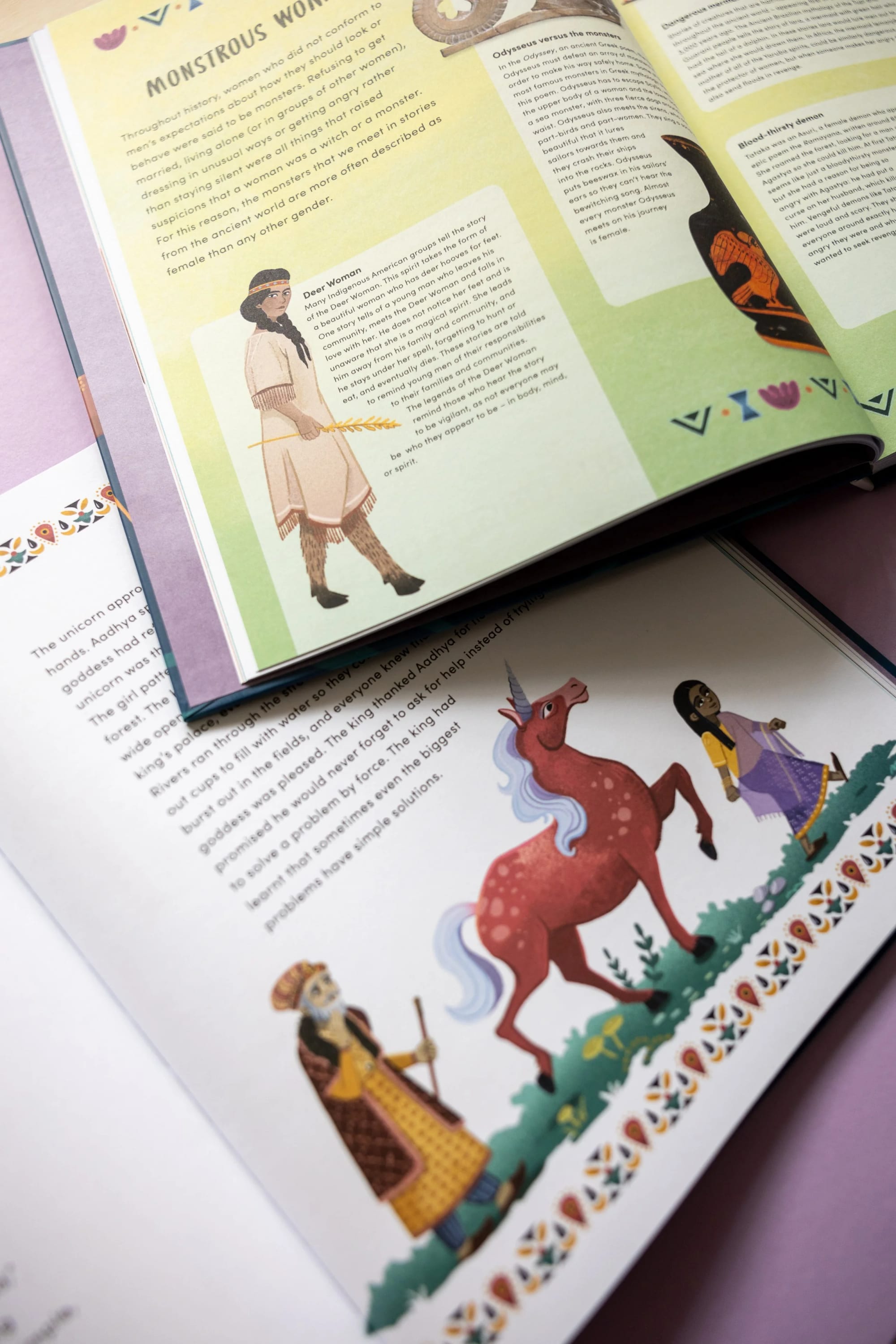 Aufgeschlagenes Kinderbuch mit Illustrationen einer Frau in traditioneller Kleidung mit Speer und eines Einhorns sowie eines Mannes in historischem Gewand daneben, vor einer verzierten Bordüre.