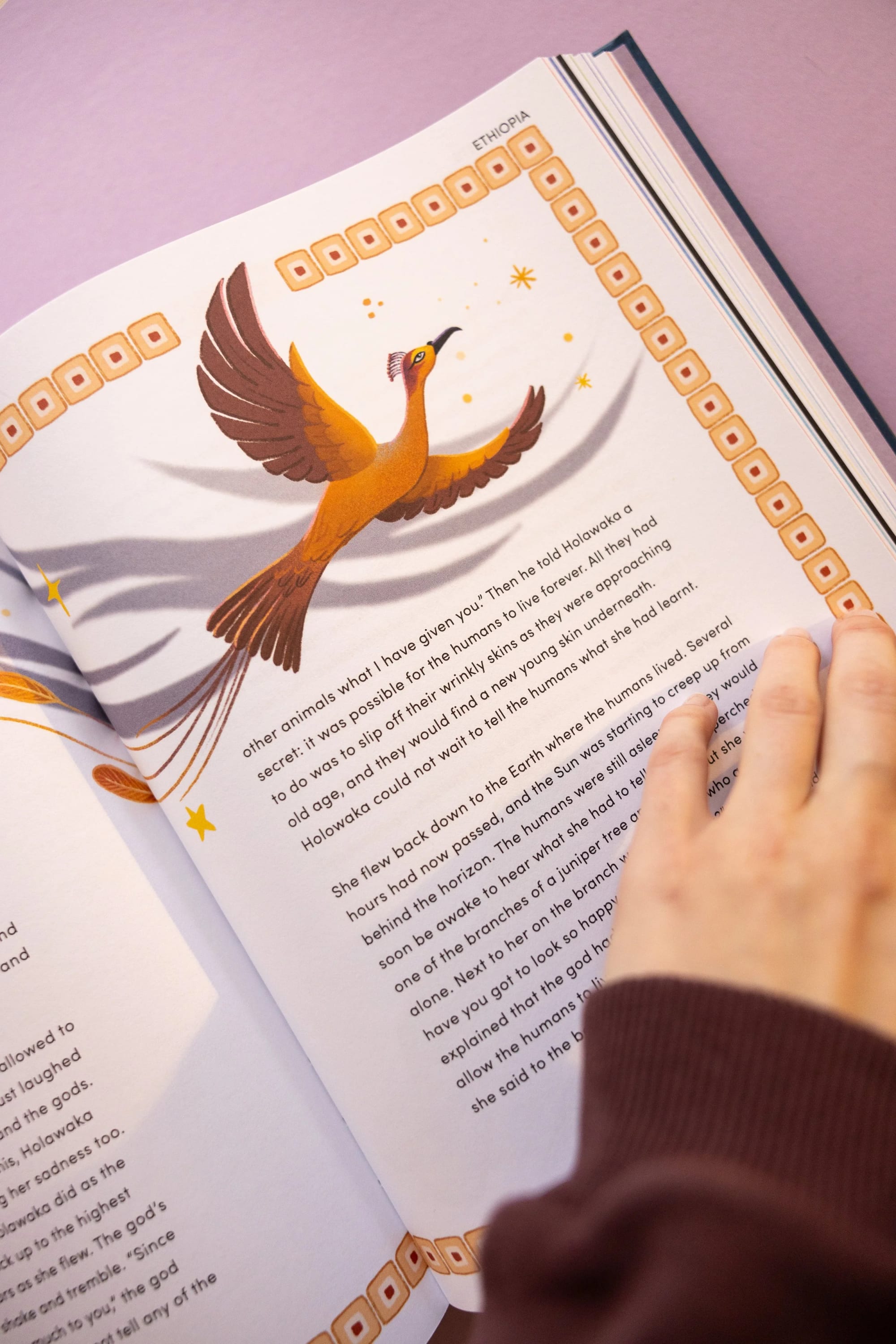 Aufgeschlagene illustrierte Buchseiten mit Text über Äthiopien und einer farbenfrohen Zeichnung eines Vogels mit ausgebreiteten Flügeln, der über dem Text fliegt.