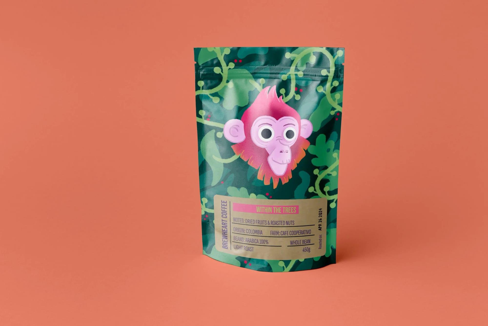 Eine farbenfrohe Kaffeetüte mit einem pinken Cartoon-Affengesicht mit großen Augen und einem Haarbüschel vor einem grünen Dschungelhintergrund. Das Etikett zeigt Kaffee aus Kolumbien mit Trockenfrüchten und gerösteten Nüssen, ganze Bohne, leichte Röstung, 450 Gramm.