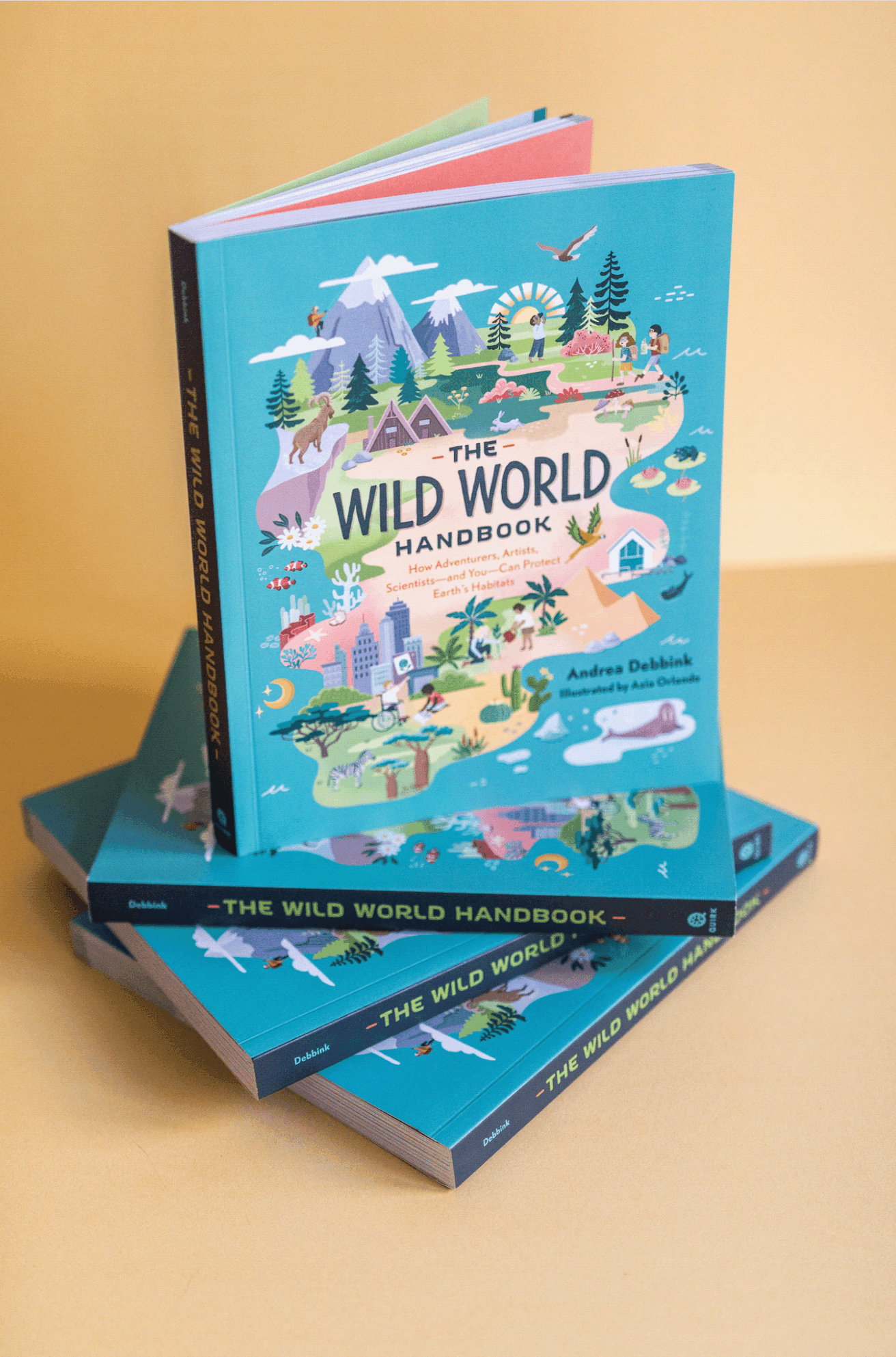 Drei Exemplare von 'The Wild World Handbook' mit einem farbenfroh illustrierten Cover, das Naturszenen, Berge, Bäume, Tiere und Menschen zeigt, auf einer gelben Fläche platziert.